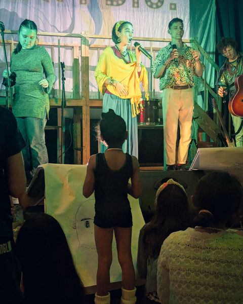 A singer in a yellow shawl performing Pinta Tu Vida live