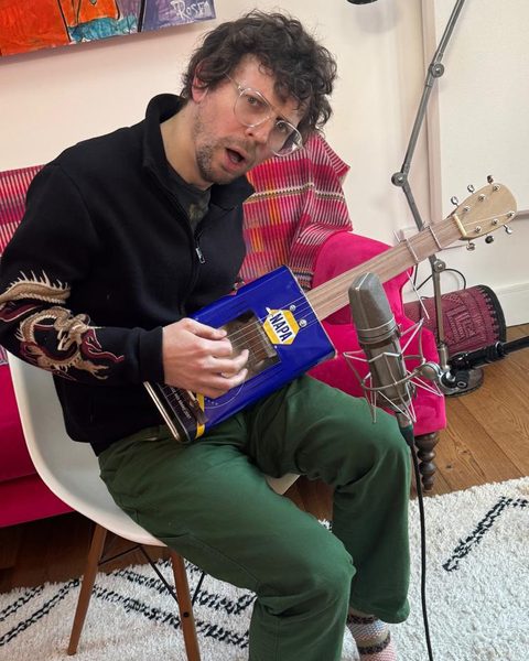 Playing a township-style oil-can guitar into a studio microphone